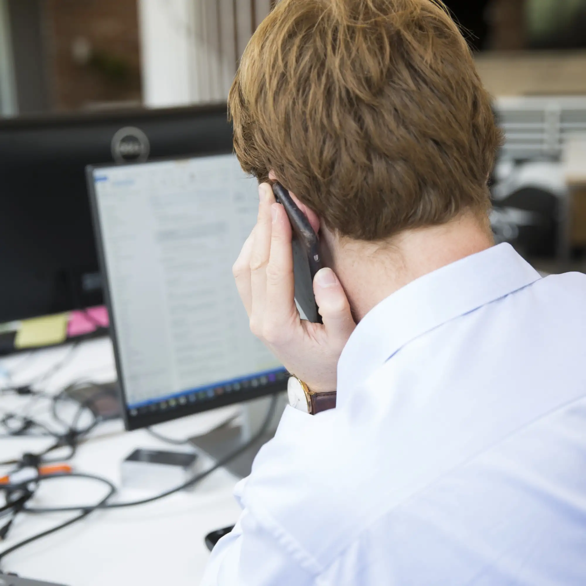 Ansatt svarer på telefon foran jobbdata på kontoret – Nettrafikk